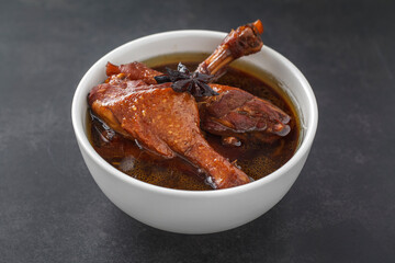 Ped Pa Lo, brown Chinese stewed calf of duck leg in white bowl on dark texture background, Thai food