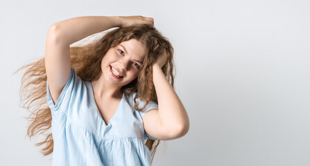 Obraz premium Portrait of attractive carefree european girl, tilting head up and shaking curly hair. Living life to fullest. Having fun and being amused. Copy space for your text