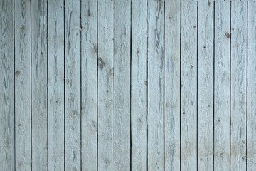 A wooden wall made of rough planks arranged vertically. The old light paint has partially collapsed, and the wood texture is visible. Background.
