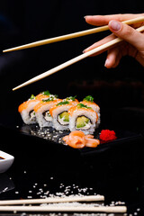 Sushi with salmon. Soy sauce, red caviar. Sushi on a black background.