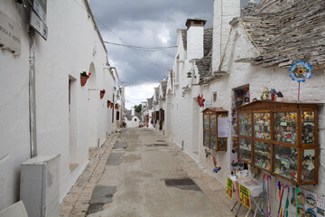 Souvenir shops and trulli along the street at Alberobello, Apulia, Italy