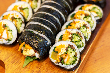 Korean kimpab rolls with vegetables and chicken on board, side view