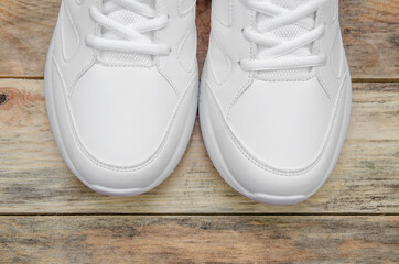 Beautiful pair of new white sneakers on a wooden background close up, view top. Sock part of sneakers close up