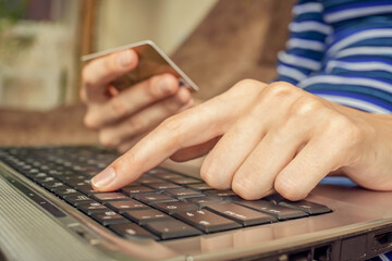 Close-up of a woman's hands holding a credit card and using a laptop. concept of online shopping