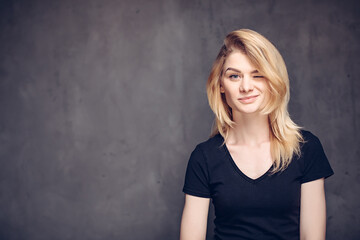 Winking young caucasian woman on dark background