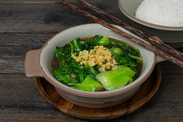 Fried Bok choy in oyster sauce with fried garlic in bowl on wooden table.