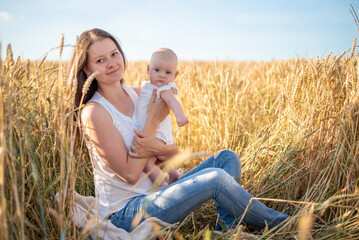 Beautiful young mother and her baby girl at the wheat field in sunny day, Czech republic