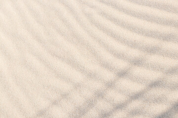 Fototapeta na wymiar Shadows and patterns on the sand of dune. Sandy beach for the background. Sand texture. Background, sand, light, beige, wave, reflect, shadow, summer.