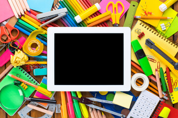 School supplies on wooden desk with digital tablet