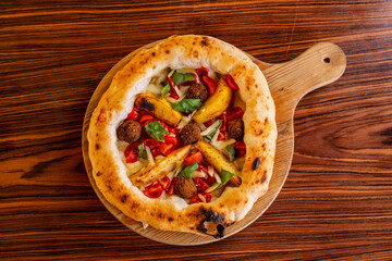 Pizza gourmet con polpette, patate al forno, pomodori, basilico e mozzarella