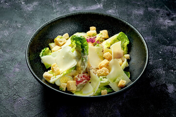 Classic Caesar salad with croutons, parmesan and white sauce in a ceramic bowl.. Close up