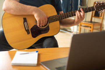 Man learns to play the guitar using online video lessons.
