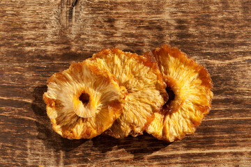 Dried pineapple slices on an old wooden board. Healthy natural sweets without added sugar. Top...
