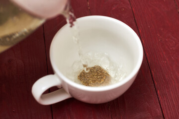 Tea bag in a white cup. Add boiling water to the cup. Making delicious herbal tea.