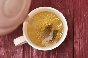 Tea bag in a white cup. Add boiling water to the cup. Making delicious herbal tea.