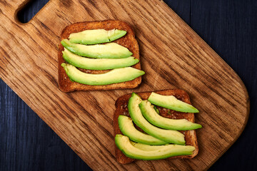Toast with sliced avocado on a wooden background.
