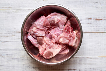 Raw rabbit in a bowl. Cutting meat, preparing for cooking.