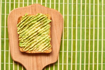 Toast with avocado on a green background.