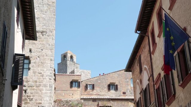 Flags flying from the facade of Banca Cambiano. In the background the Torre Chigi. San Gomignano, Tuscany, Italy, Europe