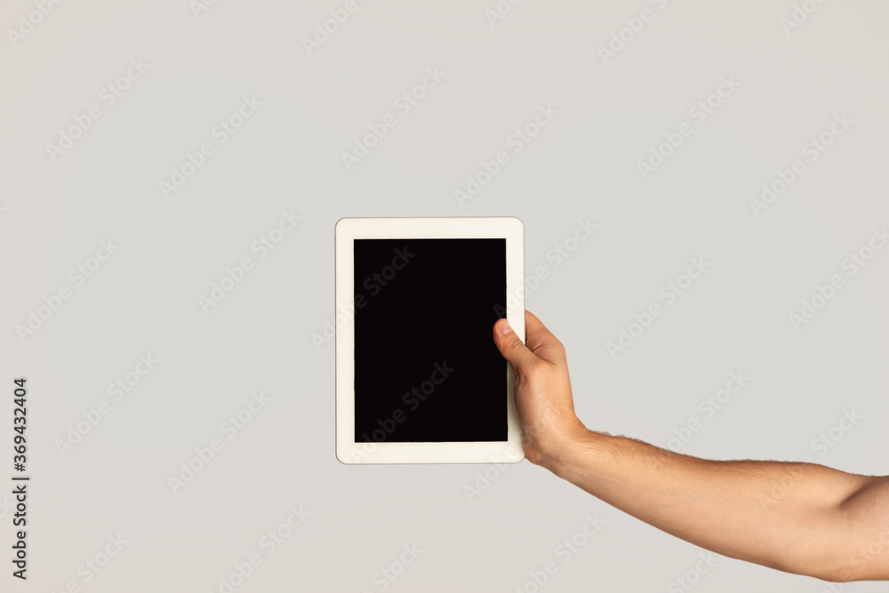 Poster Millennial guy showing tablet with blank screen on light background, mockup for website design