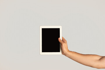 Fototapeta na wymiar Millennial guy showing tablet with blank screen on light background, mockup for website design
