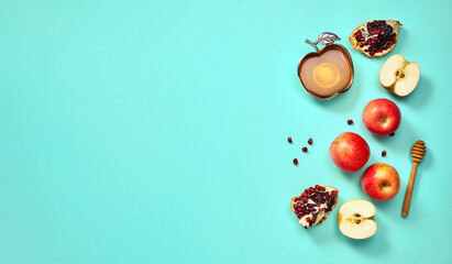 Rosh hashanah (jewish New Year holiday) concept. Traditional symbols. Apples, honey and pomegranates on a turquoise background.