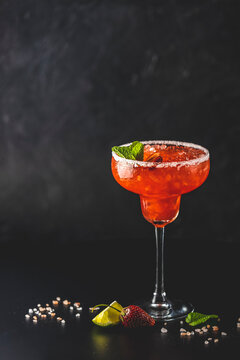 Frozen strawberry lime mint margarita in tall footed glass on the dark background. Luxury alcohol fresh drink