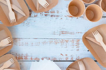 Craft tableware. Disposable tableware made from environmentally friendly materials. Composition of paper plates, glasses, knives, forks, napkins. Picnic set. View from above.