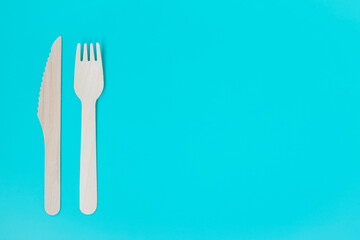 Craft. Craft disposable tableware. A wooden fork and knife lie on a turquoise background.