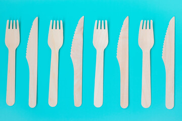 Fototapeta na wymiar Disposable tableware. Composition of tree forks and knives on a turquoise background.