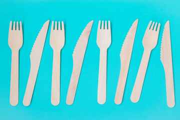 Fototapeta na wymiar Disposable tableware made from environmentally friendly materials. Composition of tree forks and knives on a turquoise background.