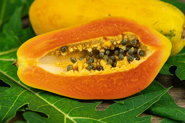 Close up papaya slice with papaya leaf on wooden table background.