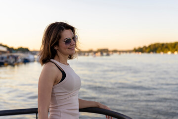 Beautiful woman wearing sunglasses at sunset by the river. Focus on the sunglasses