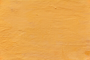 yellow-orange uneven surface of the plastered wall