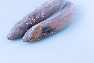 Frozen ugly bananas on a gray background. Wastefood concept. Copy space. Horizontal orientation.