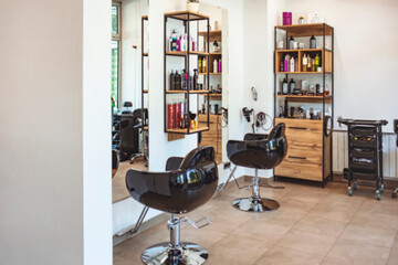 Empty black chairs and mirrors in barber shop. Interior of illuminated hair salon. Horizontal shot...