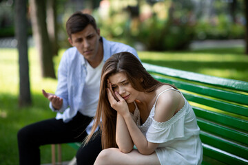 Domestic violence. Angry man and his desperate battered wife on bench at park