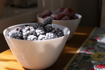 Frozen berries in white bowls on a wooden table. Selective focus. Horizontal orientation.