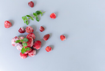 Frozen strawberries with sprigs of lemon balm on a gray background. Top view. Copy space.