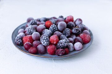 Frozen berries in a gray plate on a white background. Copy space. Close-up. Selective focus.