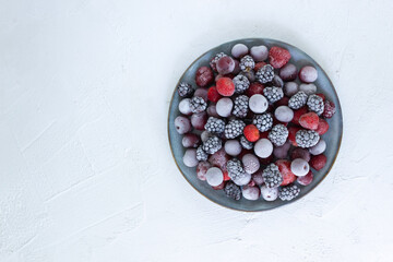 Frozen berries in a gray plate on a white background. Harvesting berries for winter. Copy space. Top view.