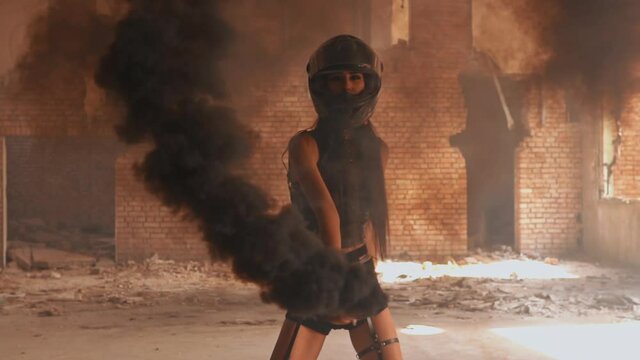 young beautiful woman in motorbike helmet waving black smoke grenade slow motion female posing in abandoned building