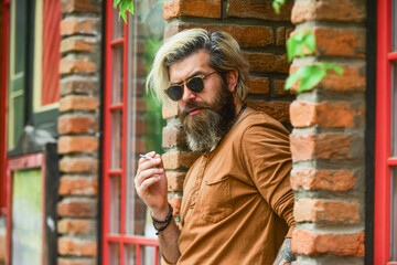 Fashionable mature man with cigarette. Brutal guy sunglasses smoking tobacco. Cool guy relaxing....