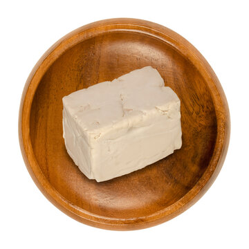 Fresh Bakers Yeast Block In A Wooden Bowl. Compressed Fresh Yeast, Used In Baking As Leavening Agent To Convert Sugars In Dough To Carbon Dioxide. Saccharomyces Cerevisiae. Close-up From Above, Photo.