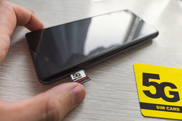 Replacing 4G SIM card with a high speed 5g SIM card close up on the store's wooden table