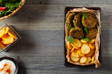 Vegetarian spinach and broccoli meatballs, served with yogurt dip and toasted potatoes. Top view.
