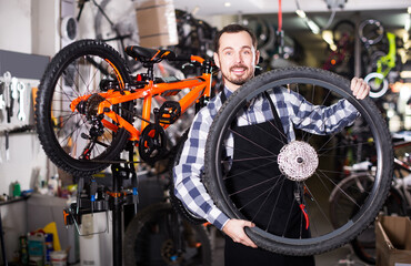 Fototapeta na wymiar Young master shows a bicycle wheel for speed bicycle in his workshop