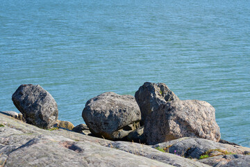 Rocks on the seacoast with blue water on the background. Copy space.