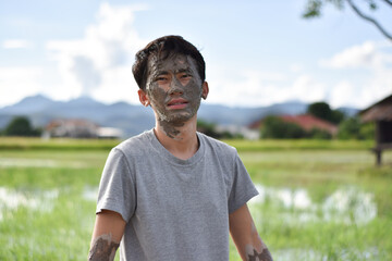 Fototapeta premium Close up of a man's face and hands covered in mud