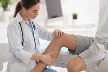 Female orthopedist examining patient's leg in clinic, closeup